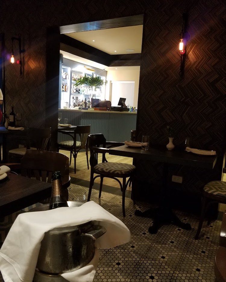 Interior oscuro de la barra con cubeta de vino y mesas vestidas