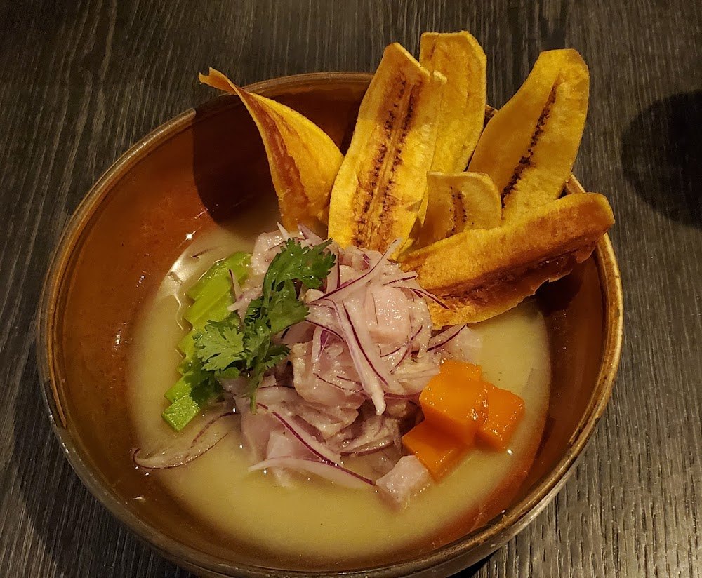 Caldo de la casa en cuenco de barro con plátano frito, jamón y vegetales