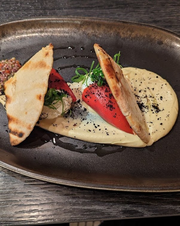 Tacos sobre plato oscuro con salsa para mojar