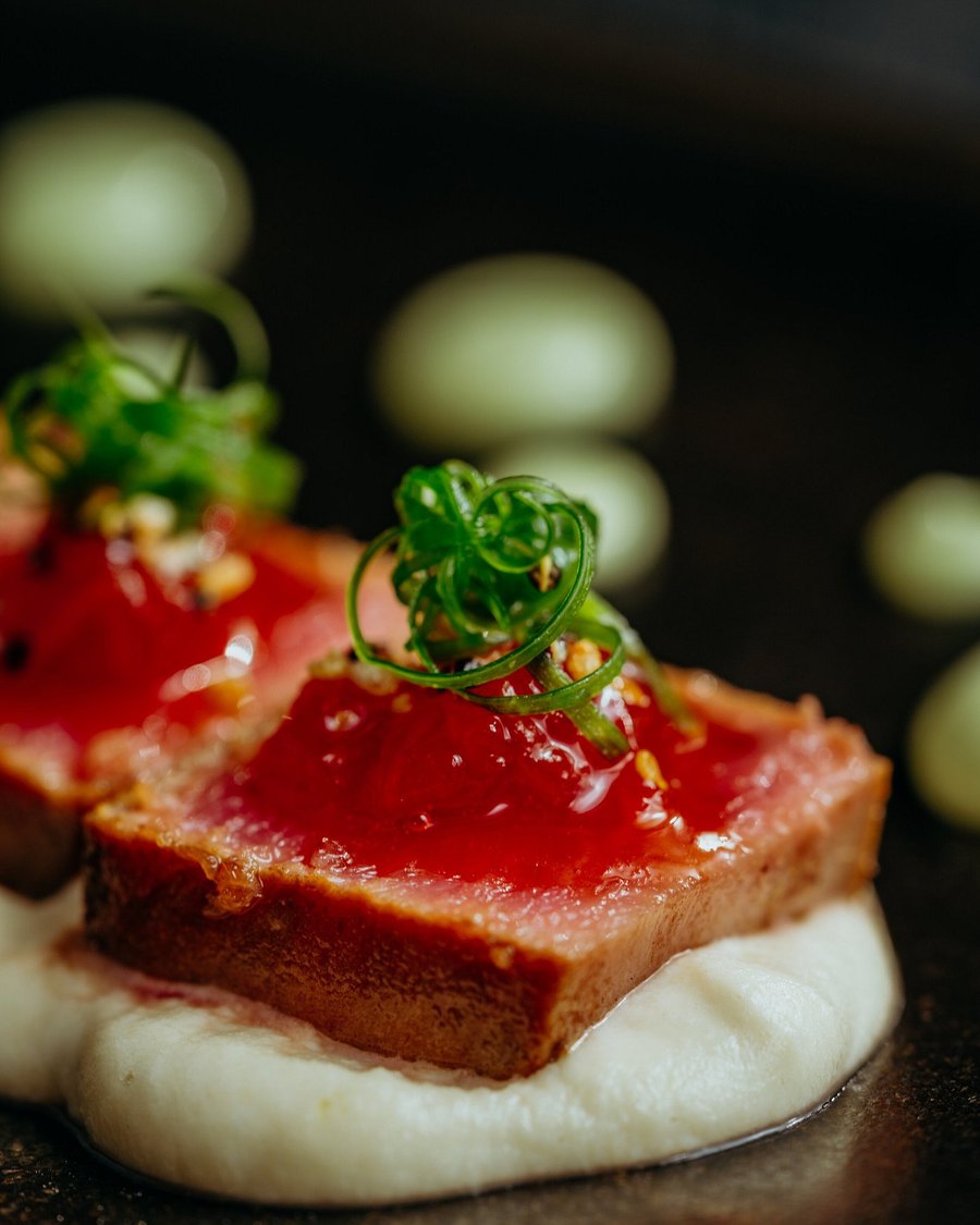 Atún sellado sobre puré blanco con salsa roja y hierbas frescas